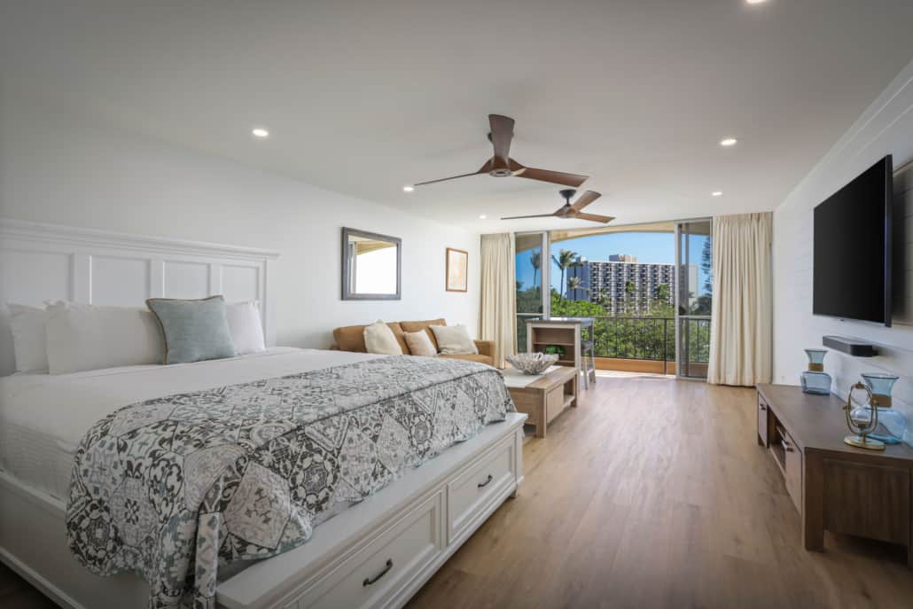 studio with bed and seperate seating with views of the outoor from the lanai