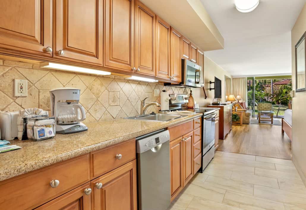 kitchen with full stove, dishwather and countertop appliacnes, looking out to the main room and beyond to the outdoor lanai