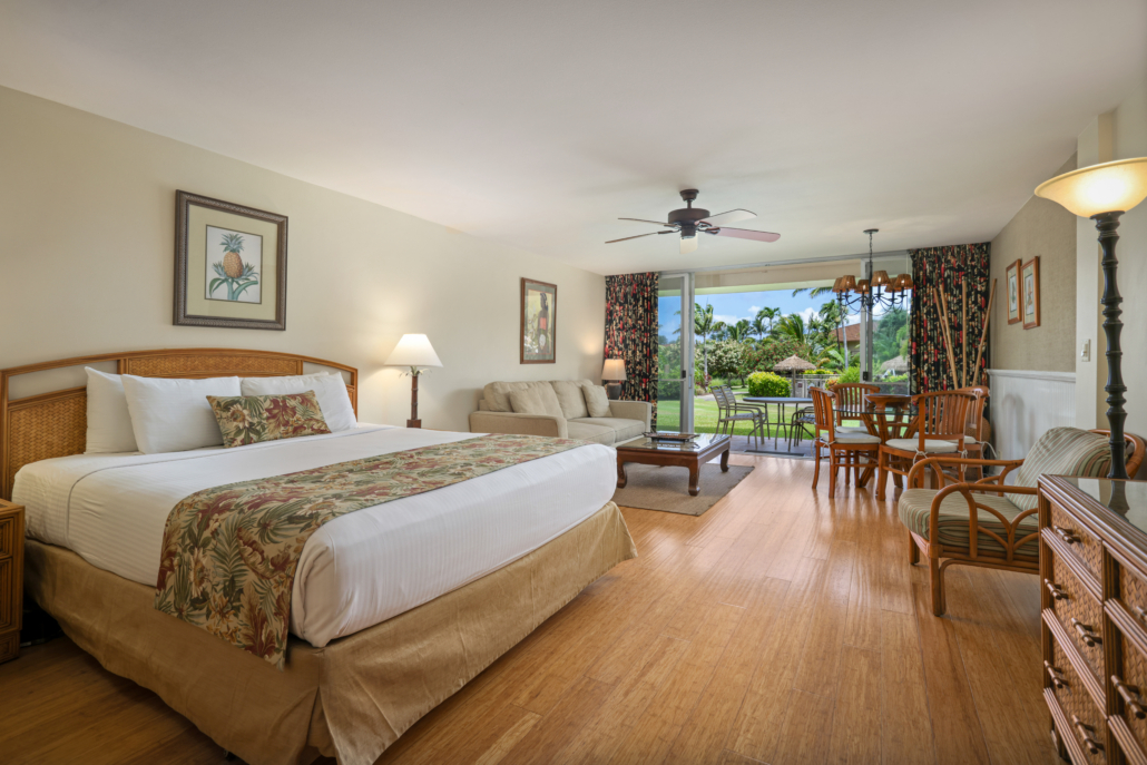 studio with bed and seperate seating with coffee table, dining area, leading to the covered outdoor lanai with seating for four