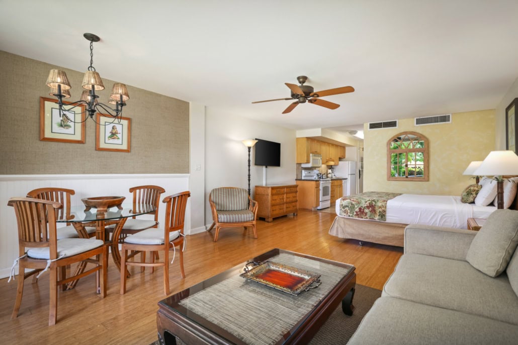 looking into the studio room with seperate seting, coffee table, separate dining area, wall mounted television looking into the kitchen
