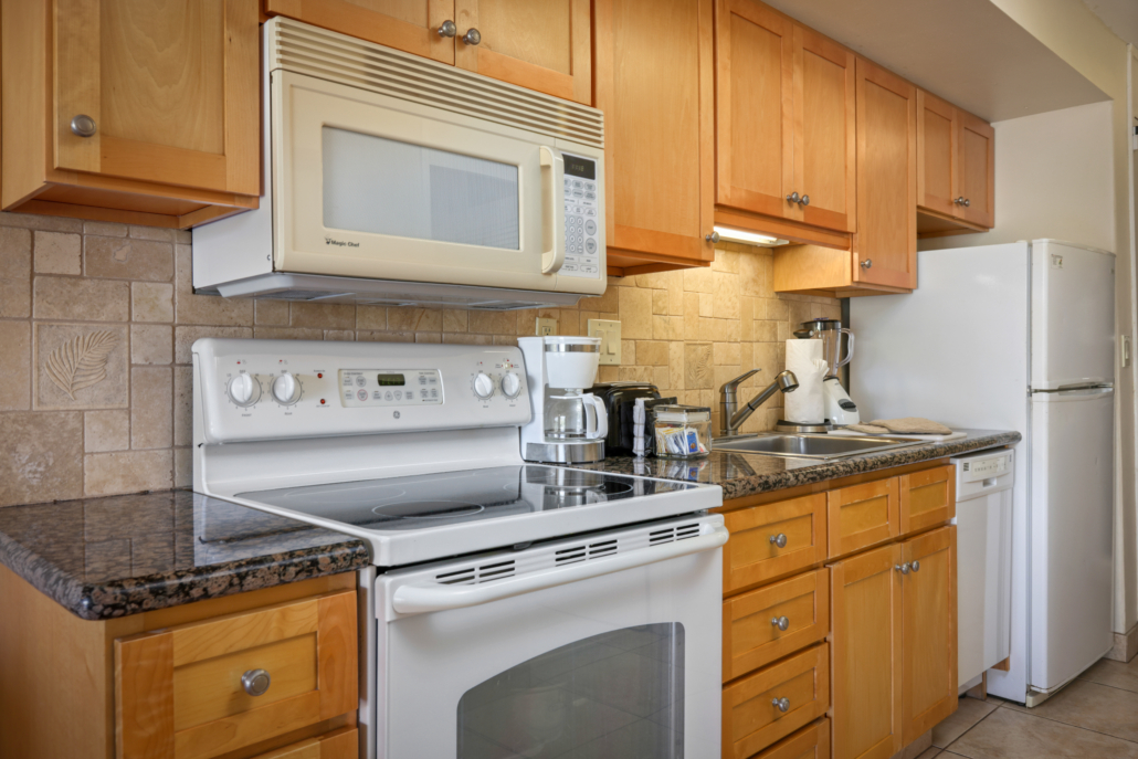studio kitchen with full-side refrigerator, counter top appliances, stove and microwave