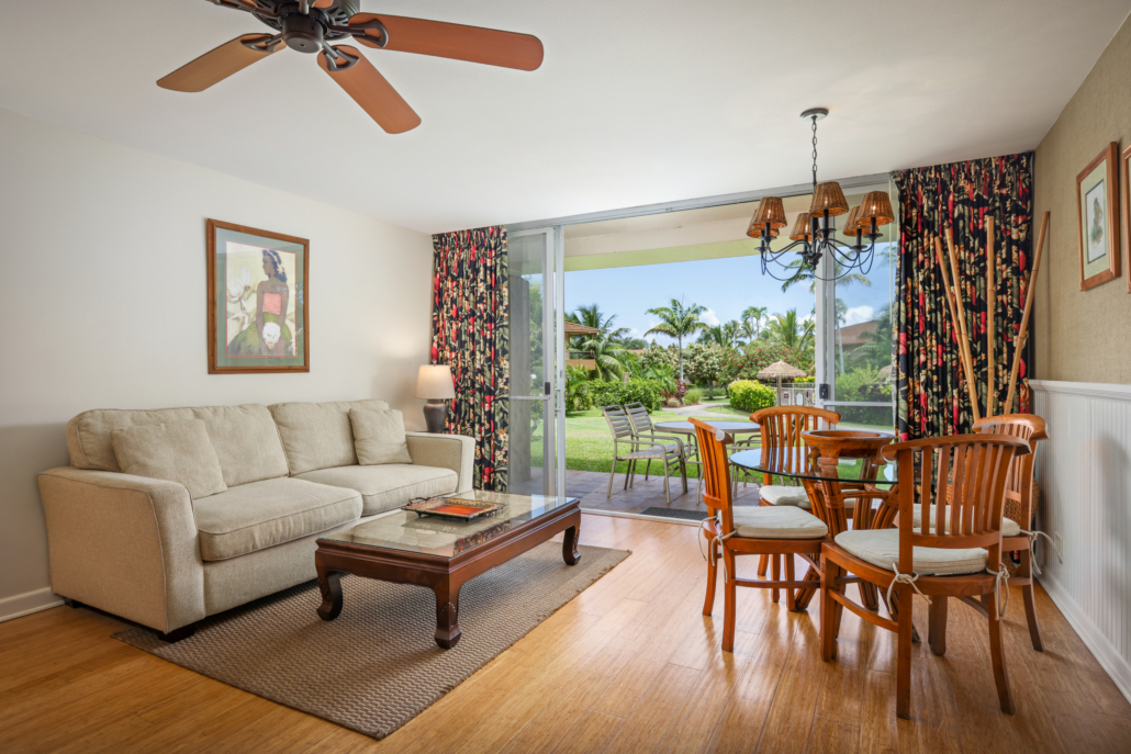 living room with separate seating area and dining area for four, covered lanai with seating and views of the garden and gated pool