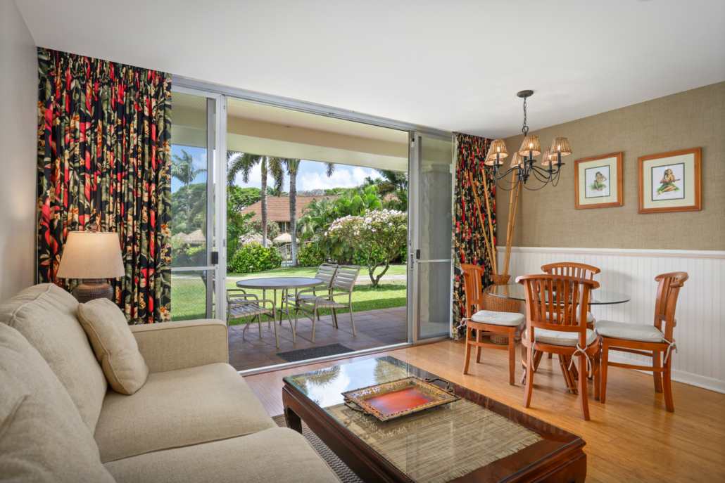 living room with separate seating area and dining area for four, covered lanai with seating and views of the garden and gated pool