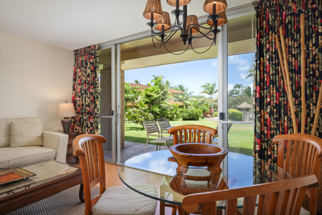living room with separate seating area and dining area for four, covered lanai with seating and views of the garden and gated pool
